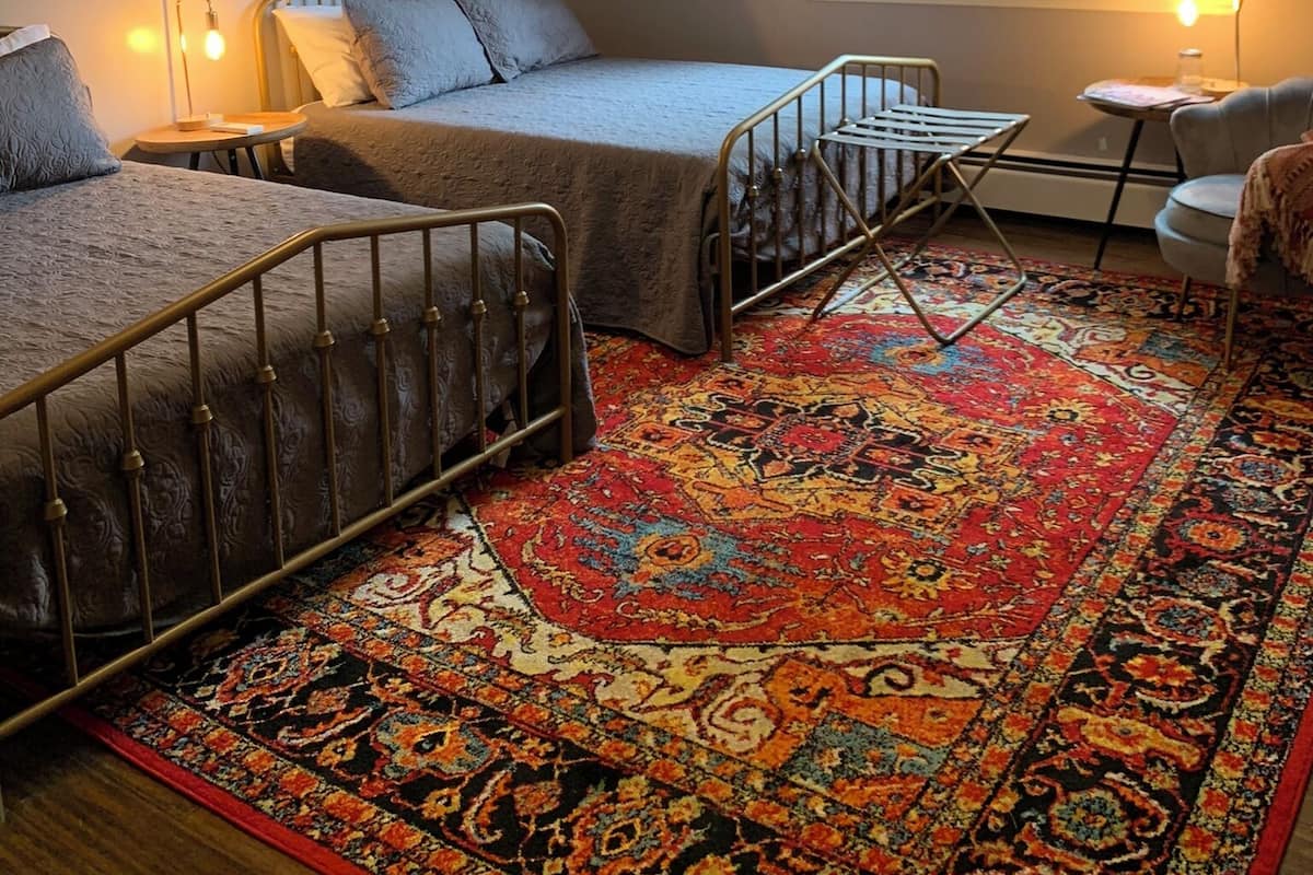 Un dormitorio con dos camas, un ventanal grande y un candelabro.