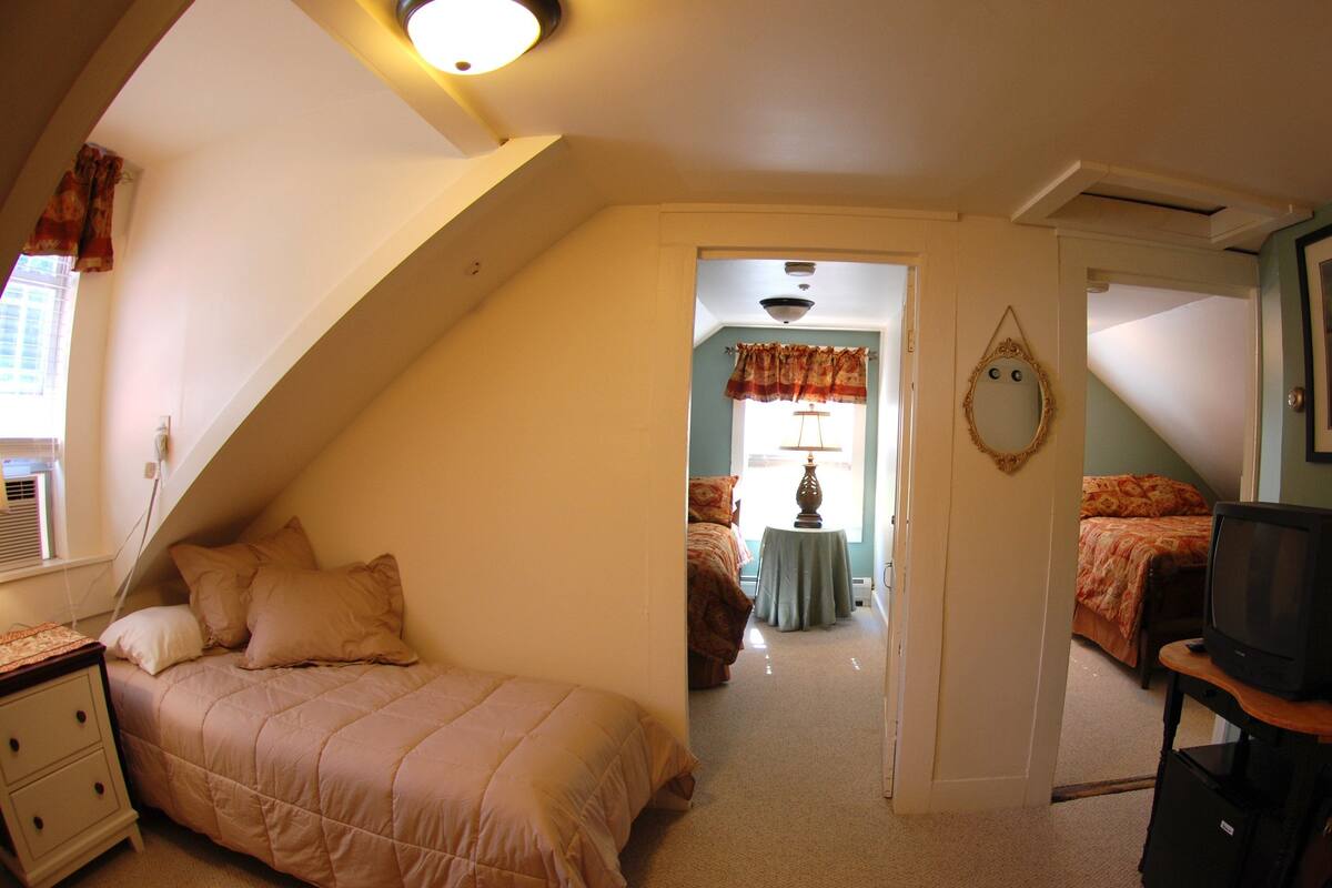 Quarto com cama, mesa de cabeceira, cômoda e televisão.
