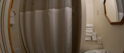 A bathroom with a shower curtain, a sink, and a mirror.