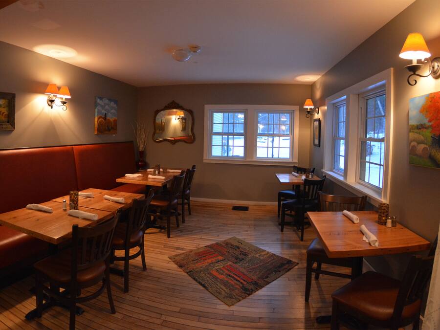 Een restaurant met zitjes en tafels, houten vloeren en wandlampen.