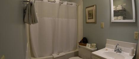 Ein Badezimmer mit Badewanne, Toilette, Waschbecken und Spiegel.