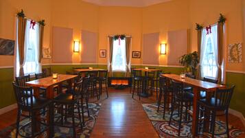 A dining area with wooden tables and chairs, a fireplace, and decorative curtains.