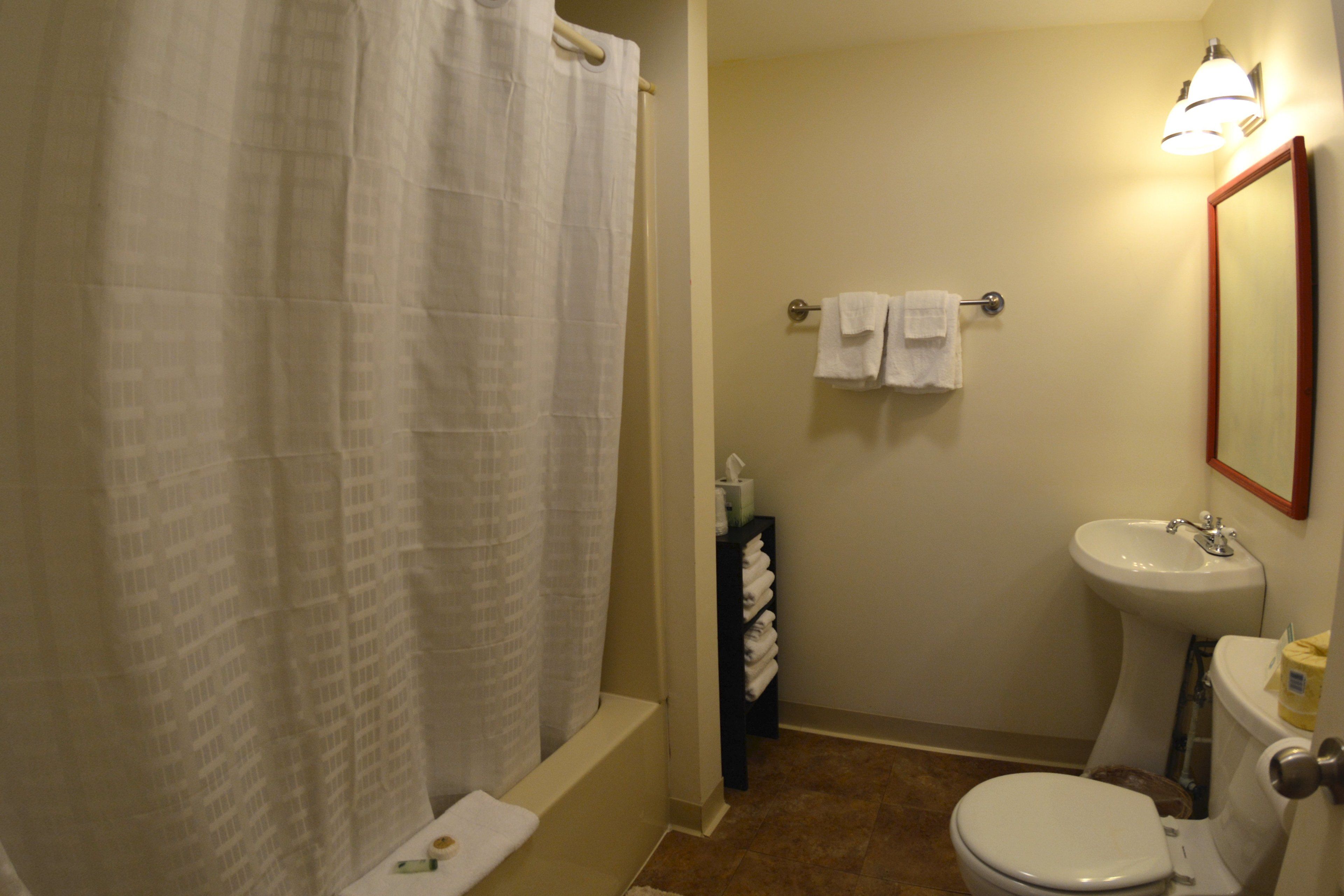A bathroom with a bathtub, toilet, sink, and a mirror.