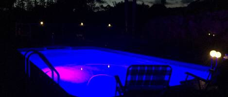 Een buitenzwembad, ligstoelen bij het zwembad