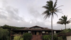 A two-story building with a staircase leading to the entrance, surrounded by lush greenery and palm trees. - Hawaii Island Resort (Naalehu)