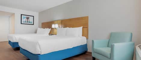 A hotel room with a large bed, a chair, a nightstand, and a framed picture on the wall.