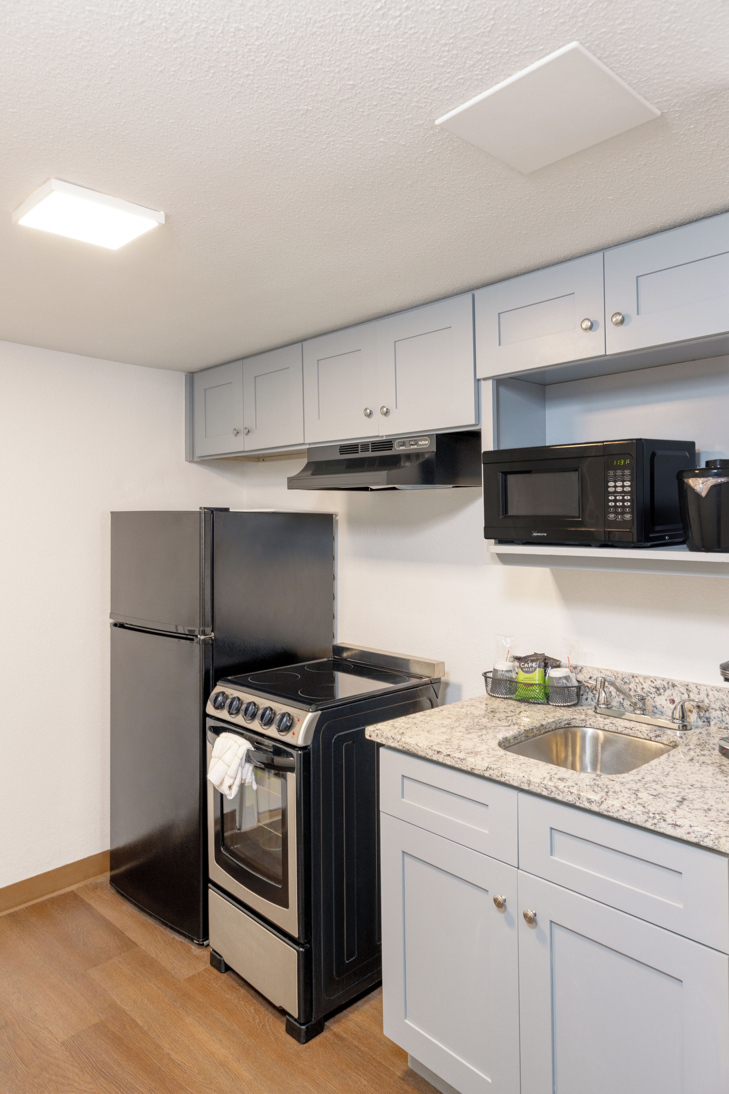 Una cocina con un refrigerador de acero inoxidable, una estufa negra, un microondas y gabinetes azul claro.
