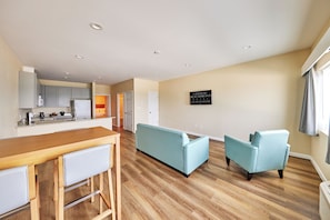 Una sala de estar moderna con cocina, una mesa de comedor de madera y un sofá azul claro.
