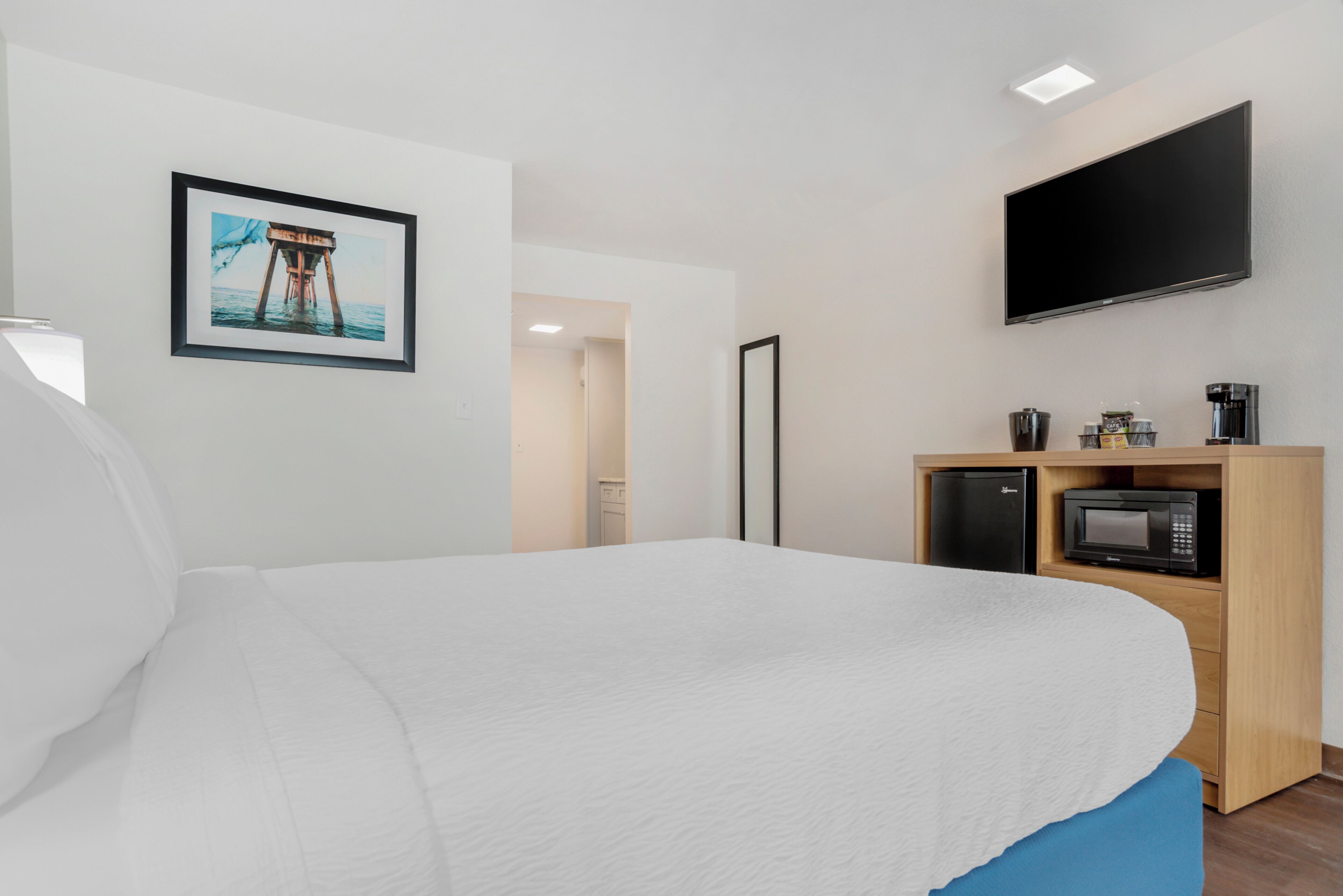 A hotel room with a bed, a flat-screen TV, a microwave, and a coffee machine.