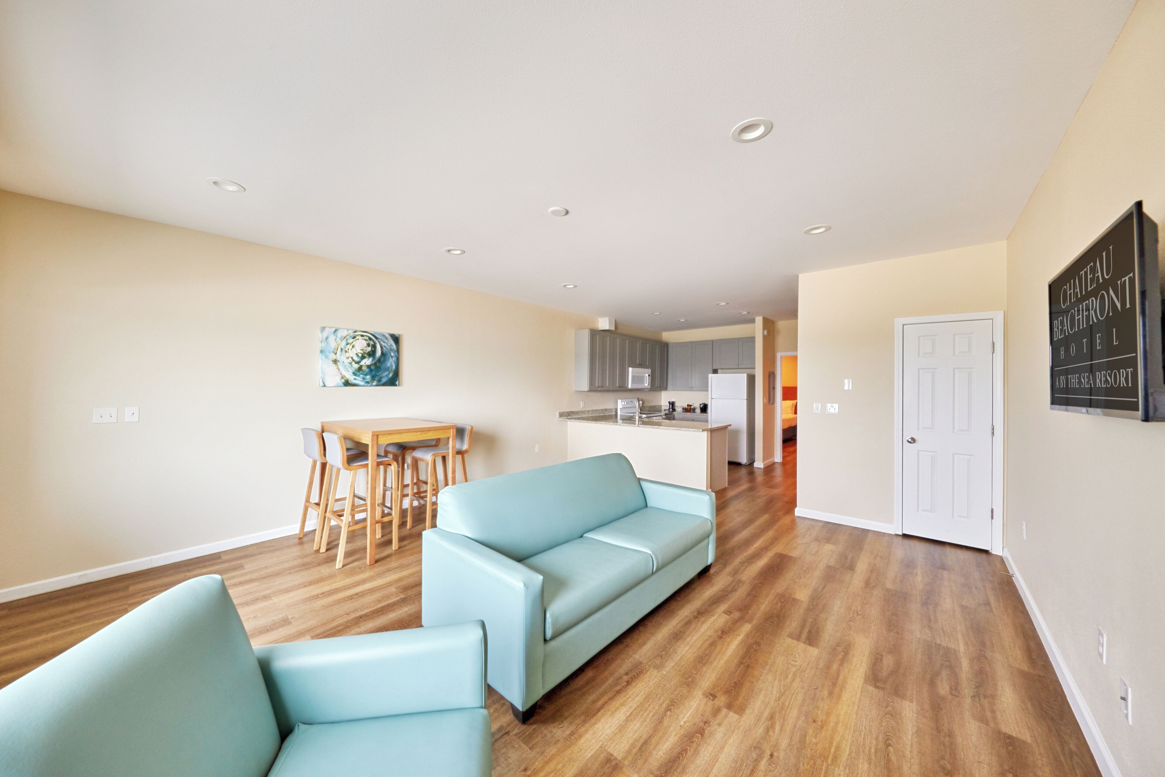 A modern living room with a light blue sofa, a dining area with a wooden table, and a kitchen in the background.