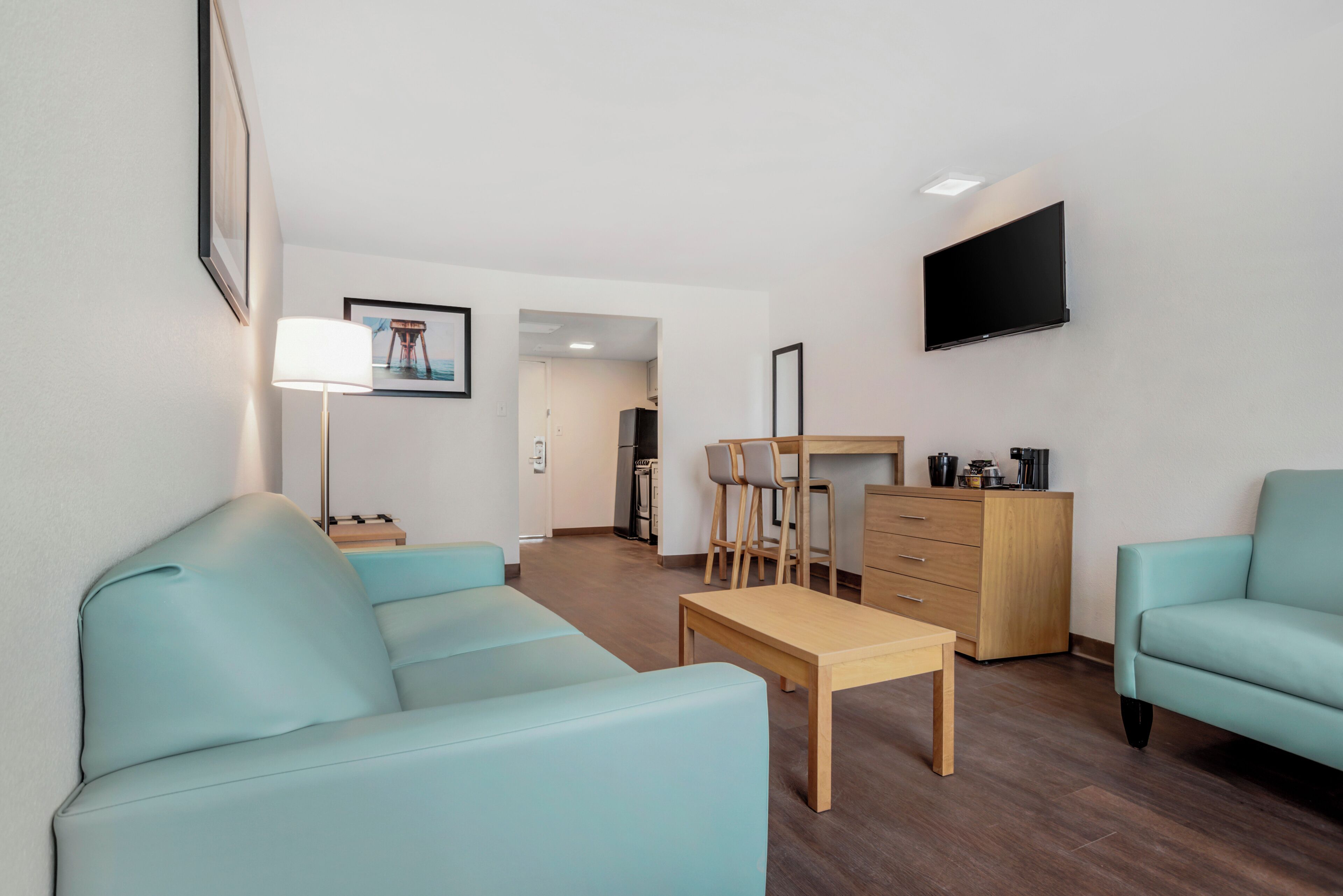 Un salon moderne comprenant un canapé, une table basse, un téléviseur et un bureau avec des chaises.