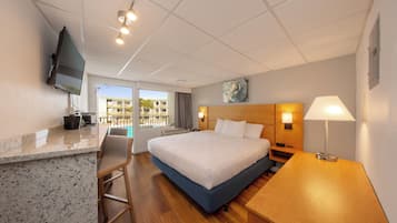 Habitación de hotel con cama, escritorio, silla, televisión y ventana con vistas a edificios.