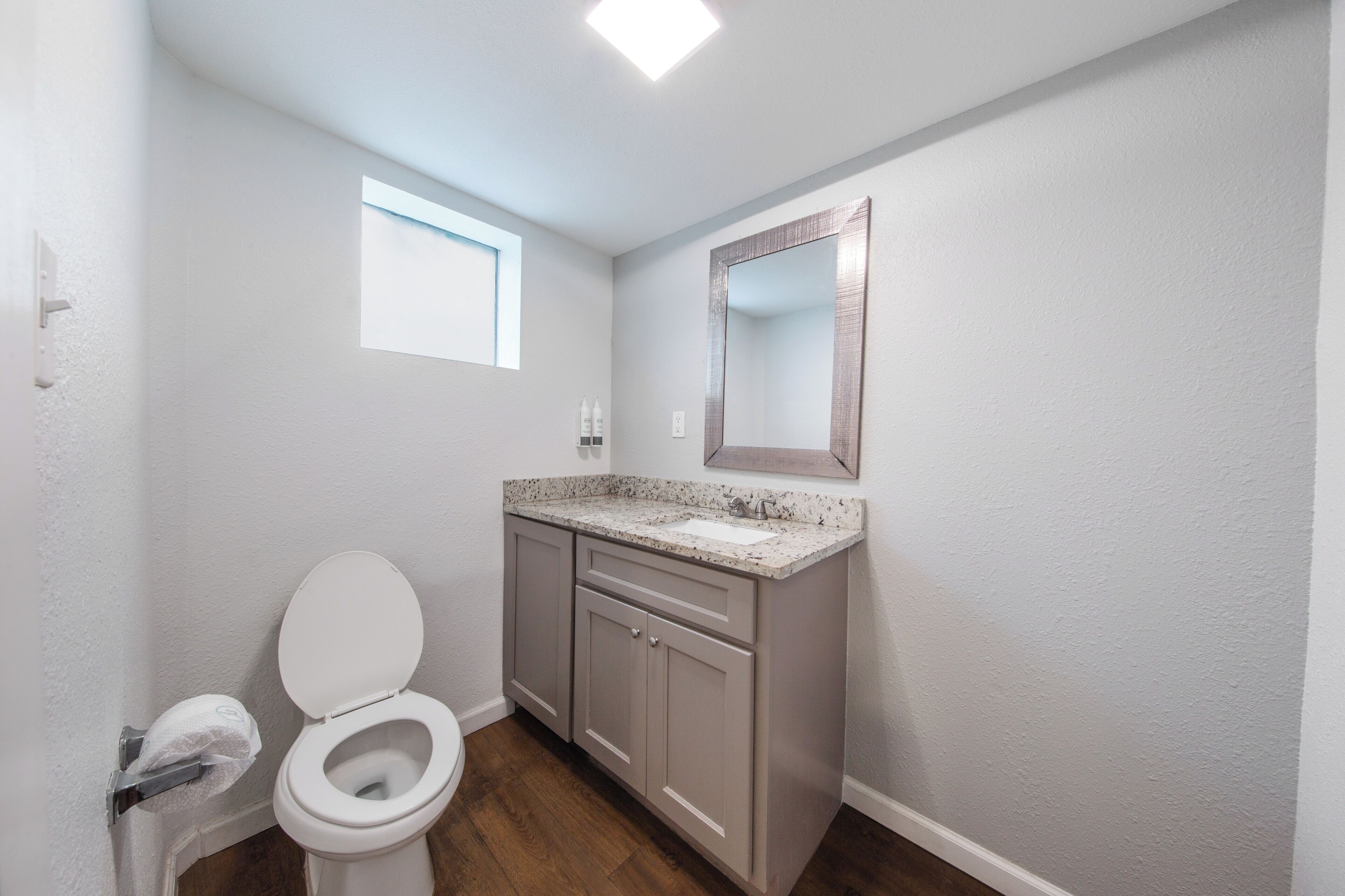 A bathroom with a toilet, sink, and mirror.
