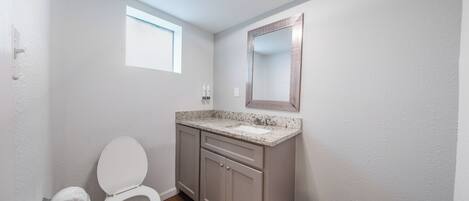 Un baño con inodoro, lavamanos y espejo.