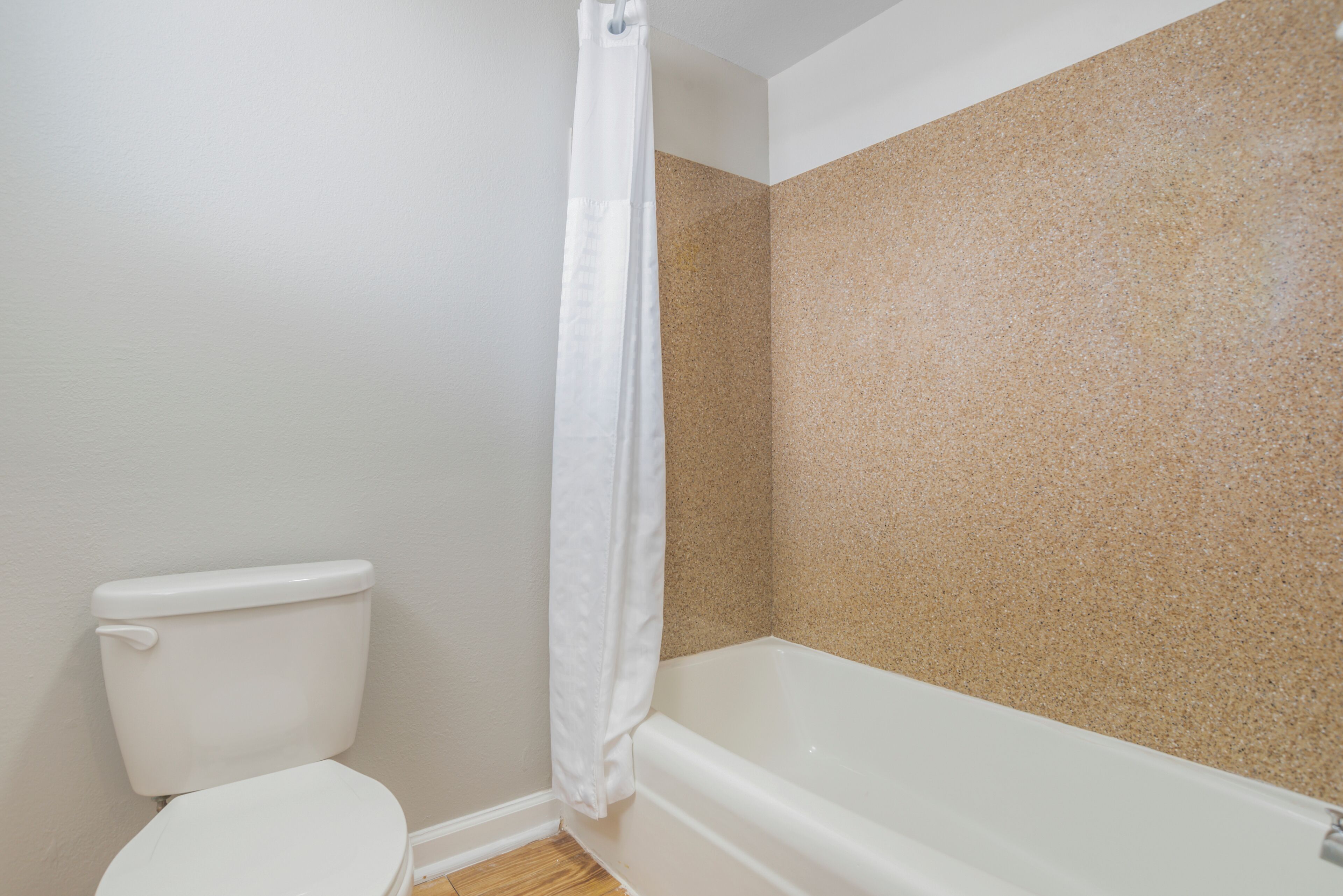 Un baño con inodoro, bañera y cortina de ducha.