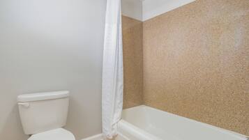 Un baño con inodoro, bañera y cortina de ducha.