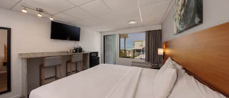 A hotel room with a bed, a desk with a chair, a TV mounted on the wall, and a window with a view.