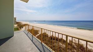 A balcony with a view of a beach and a pier.