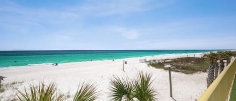 Une plage de sable blanc, une eau turquoise et limpide, et un ciel ensoleillé.