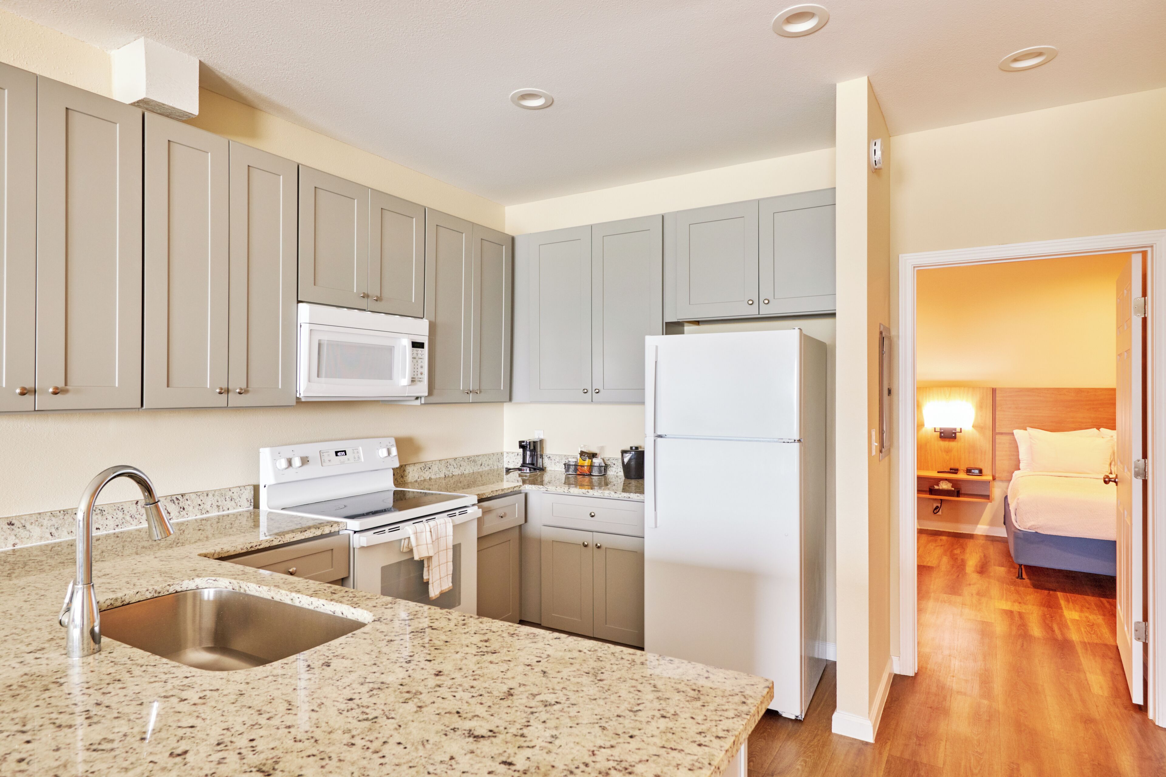 Una cocina moderna con encimeras de granito, electrodomésticos de acero inoxidable y armarios de color gris claro.
