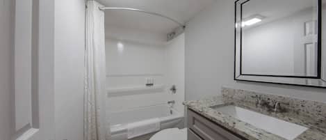 Un baño con bañera, inodoro, lavabo y espejo.