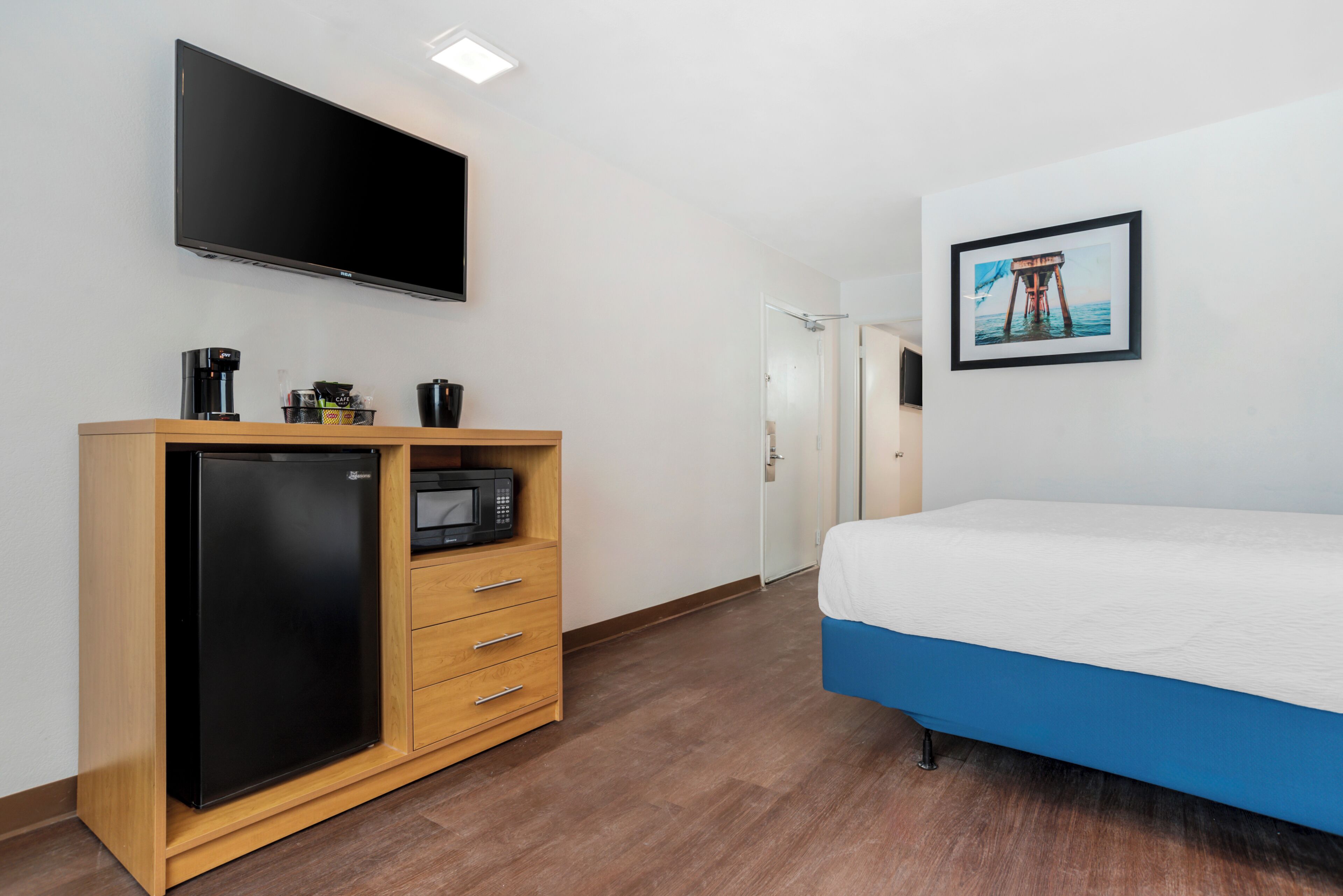 Ein Schlafzimmer mit einem Bett, einem an der Wand montierten Fernseher, einem Kühlschrank und einer Mikrowelle.