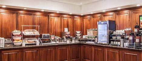 Una cocina de hotel con armarios de madera, una estación de café y diversos alimentos a la vista.