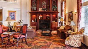 A spacious living room with a fireplace, a balcony, and a large window with curtains.