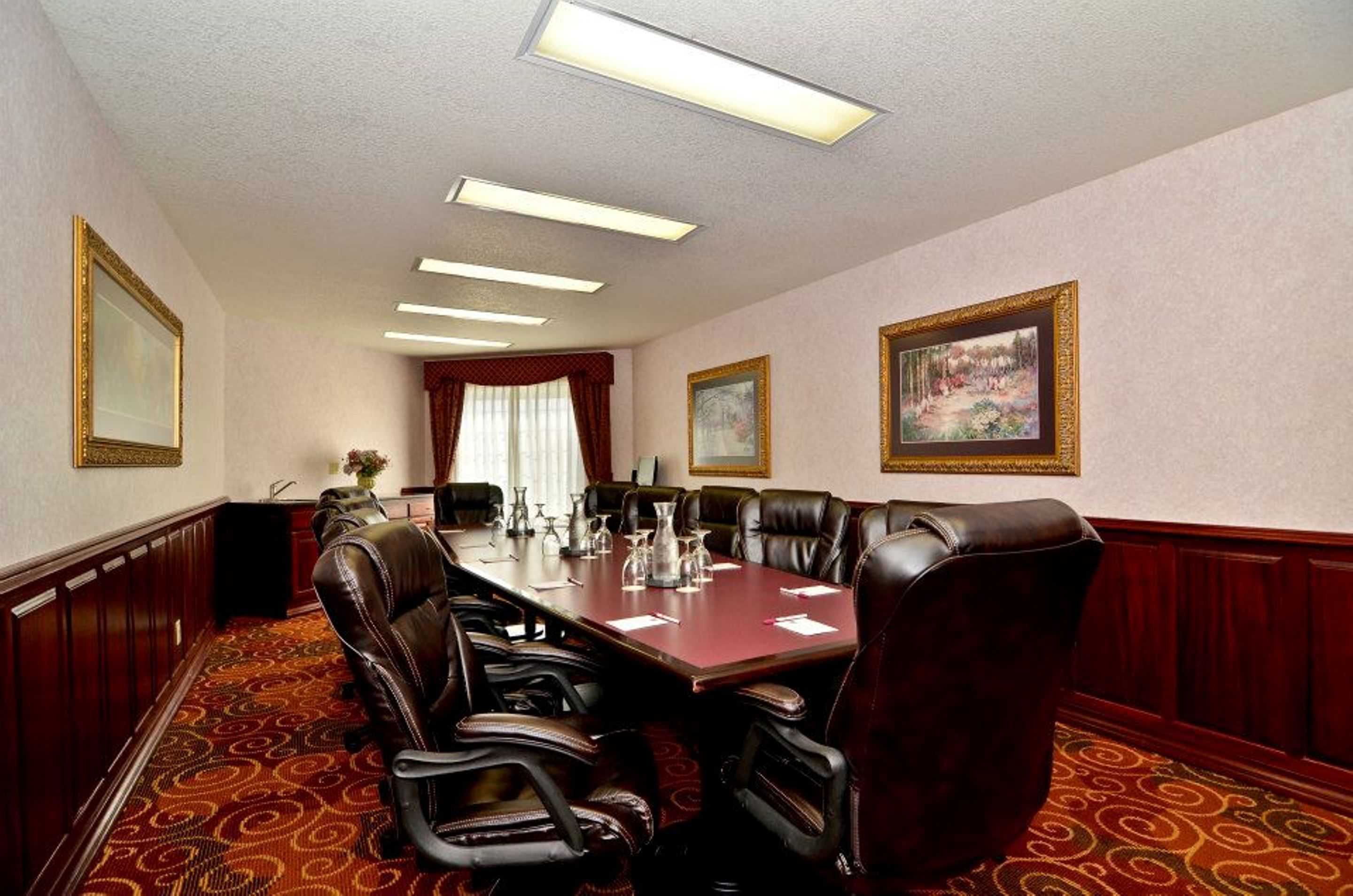 A conference room with a long table, leather chairs, and framed pictures on the walls.