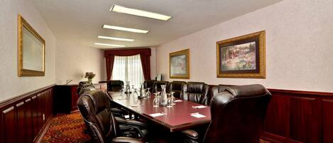 A conference room with a long table, leather chairs, and framed pictures on the walls.