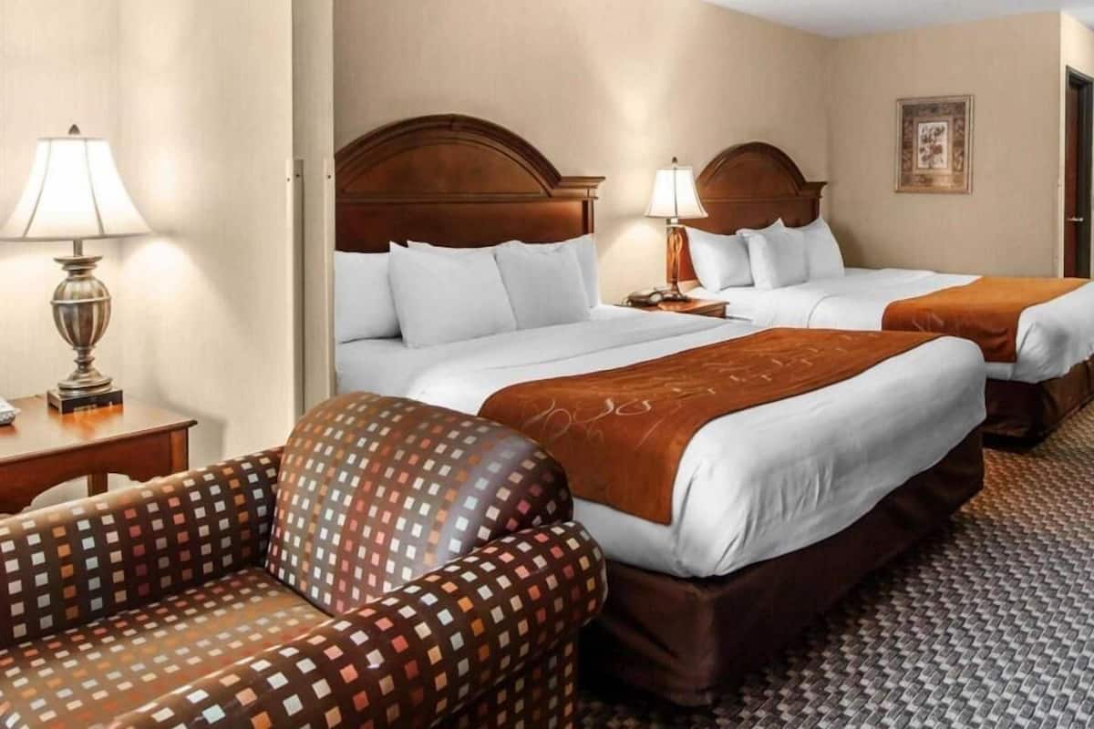 Une chambre d’hôtel avec deux lits, un canapé et une lampe.