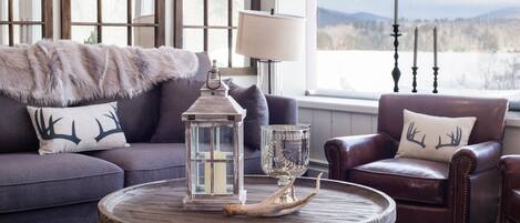 A cozy living room with a round wooden coffee table, a leather armchair, and a sofa with a fur throw.
