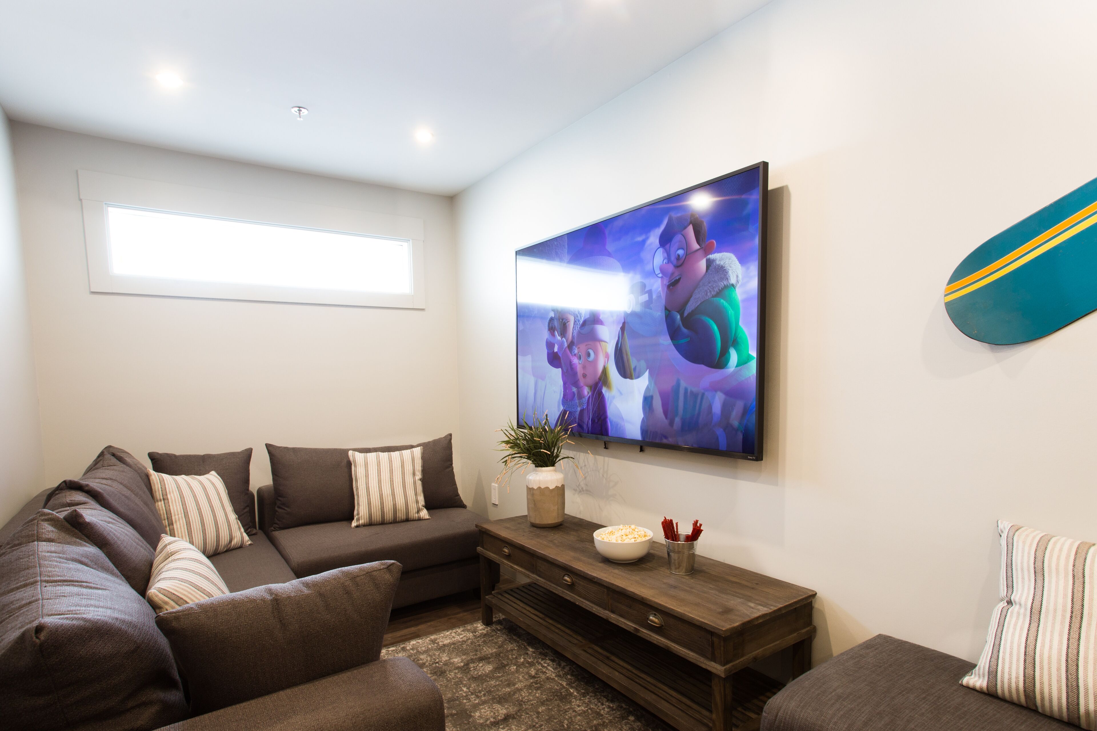Una sala de estar moderna con un sofá seccional, una mesa de centro y un televisor de pantalla plana montado en la pared.