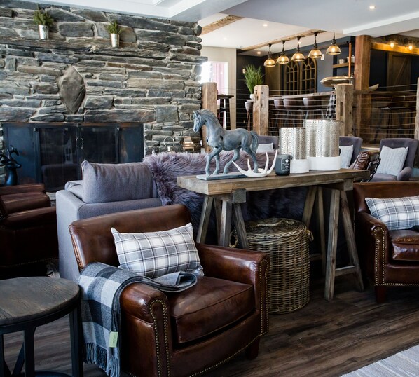 A cozy living room with leather armchairs, a stone fireplace, and rustic decor.