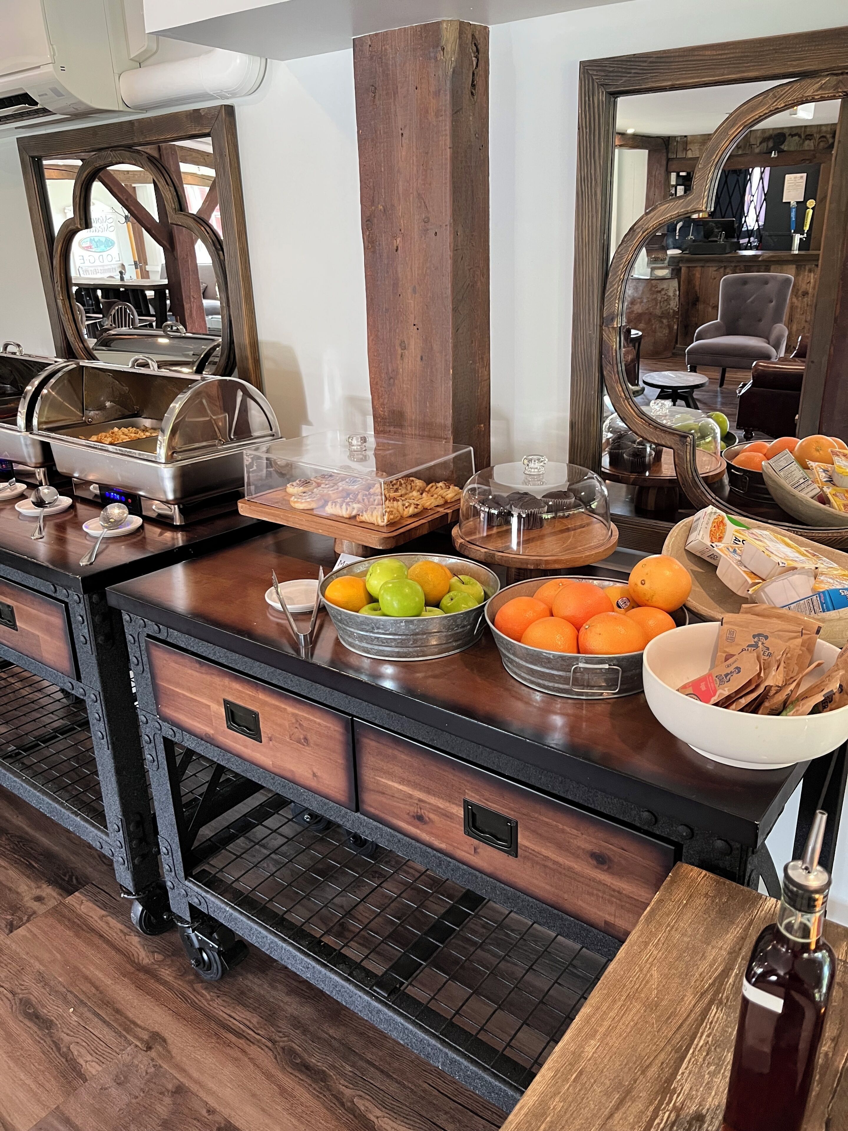 A buffet setup with various food items and a mirror reflecting the room.