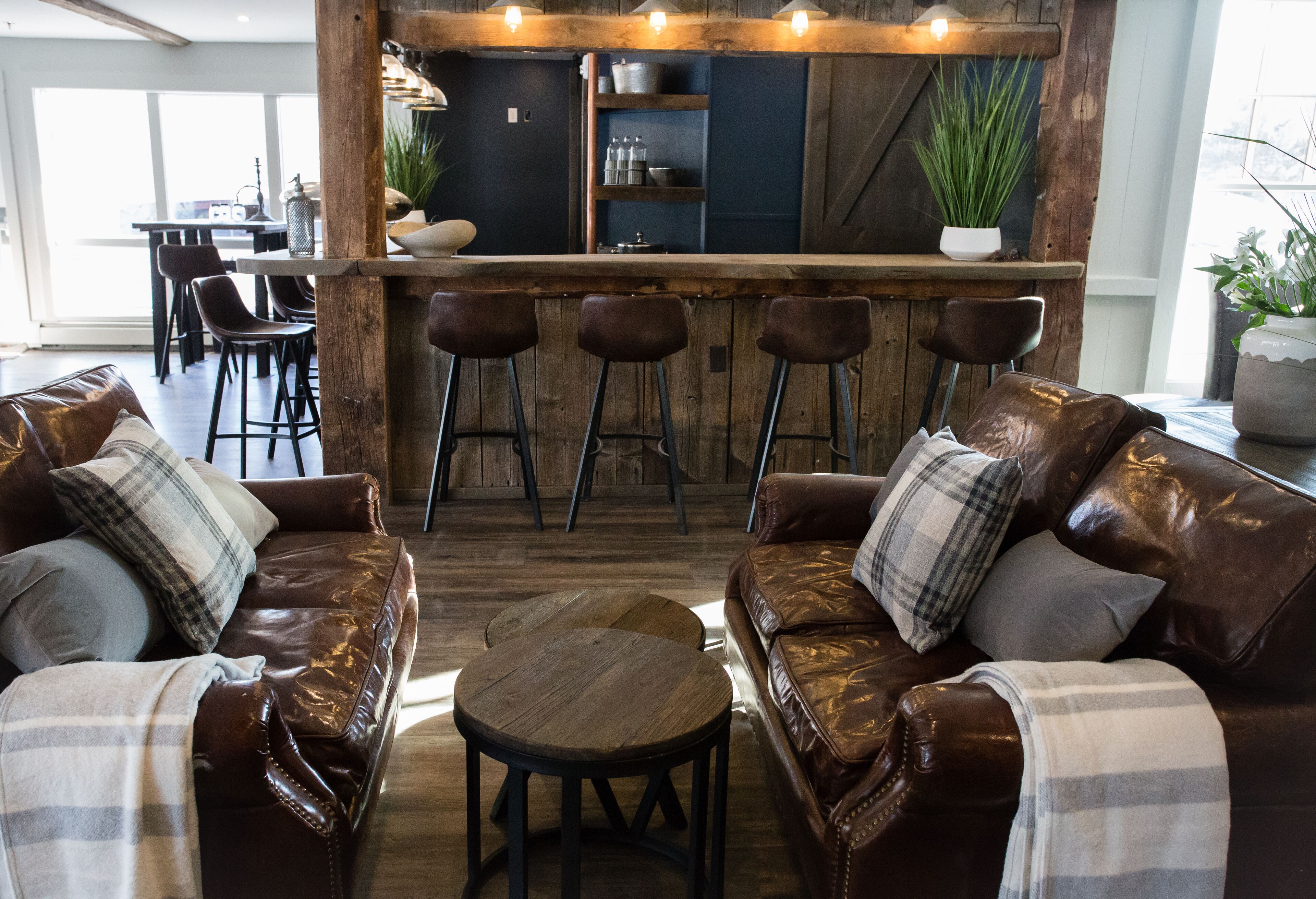Una sala de estar acogedora con sofás de cuero, una mesa de centro de madera y una barra con taburetes.