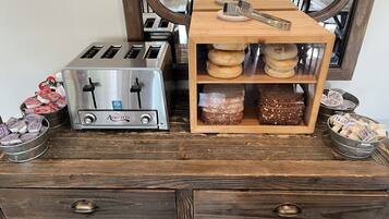 Una kitchenette con un tostador, una caja de pan de madera y un bol de aperitivos de metal.
