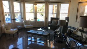 A spacious living room with a large window, a fireplace, and a chandelier. - Hotel St. Lauren (Avalon)