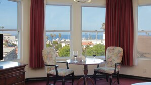 A room with a view of the ocean, a table with two chairs, and a dresser. - Hotel St. Lauren (Avalon)