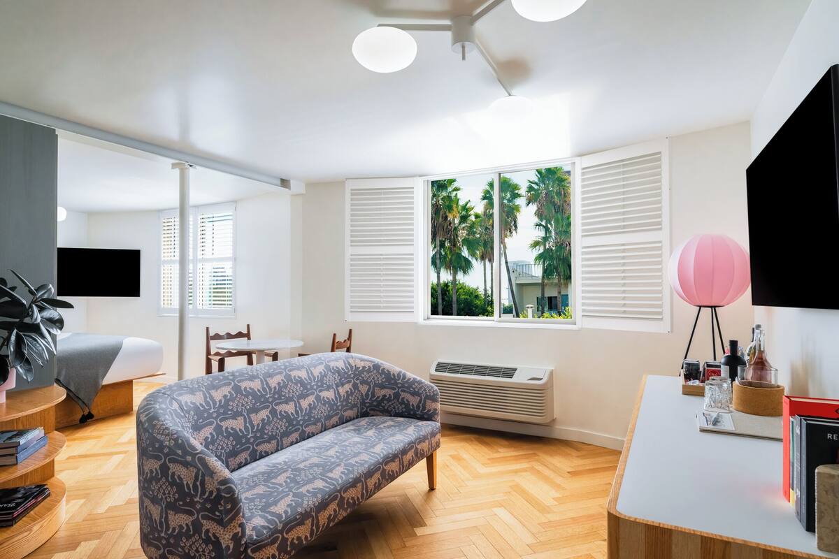 A modern living room with a patterned sofa, a dining table, and a TV.