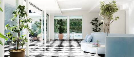 A modern living room with a checkered floor, a blue sofa, and potted plants.