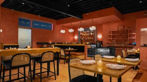 A restaurant interior with wooden tables and chairs, a bar area, and shelves with bottles. - Short Stories Hotel (Los Angeles)