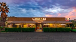 Edifício do Miners Inn com placa, entrada e área de estar ao ar livre.