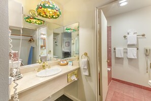 A hotel bathroom with a large mirror, a sink, a toilet, and a shower area.