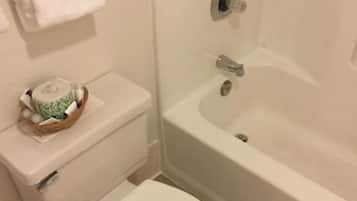 Un baño con inodoro, lavamanos blanco y bañera.