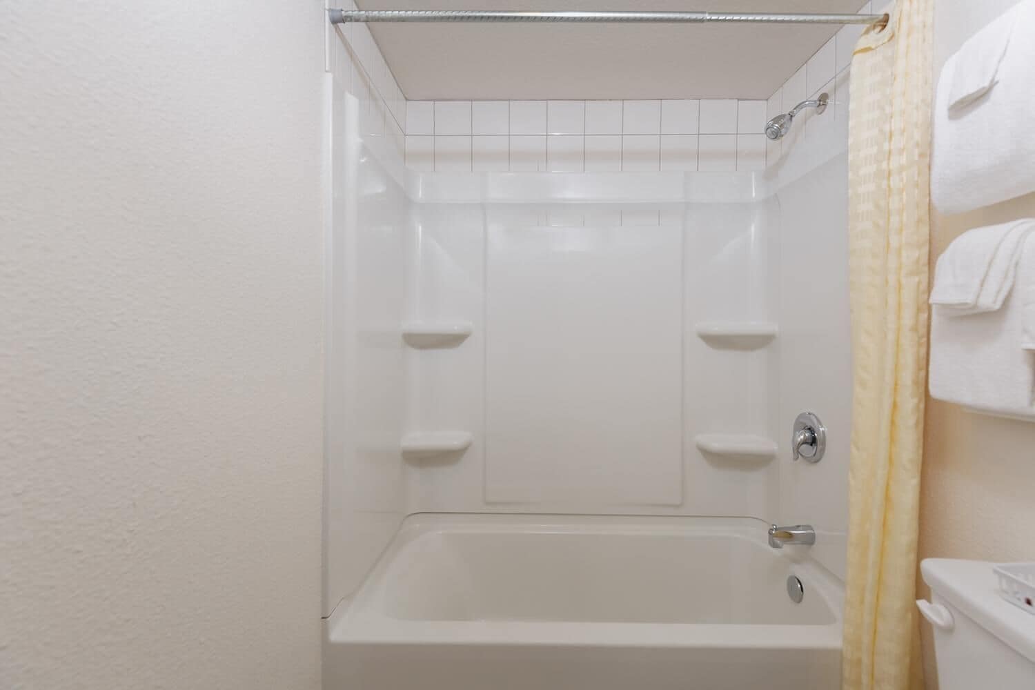 A white bathroom with a bathtub, a toilet, and a shower curtain.