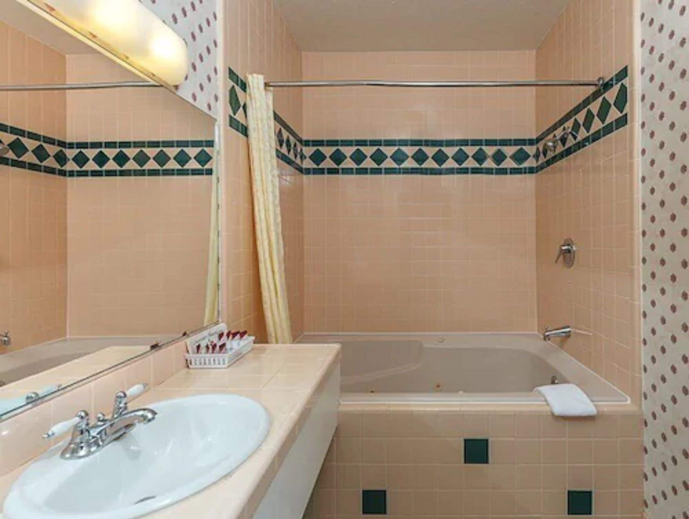 A bathroom with a bathtub, a sink, and a mirror.