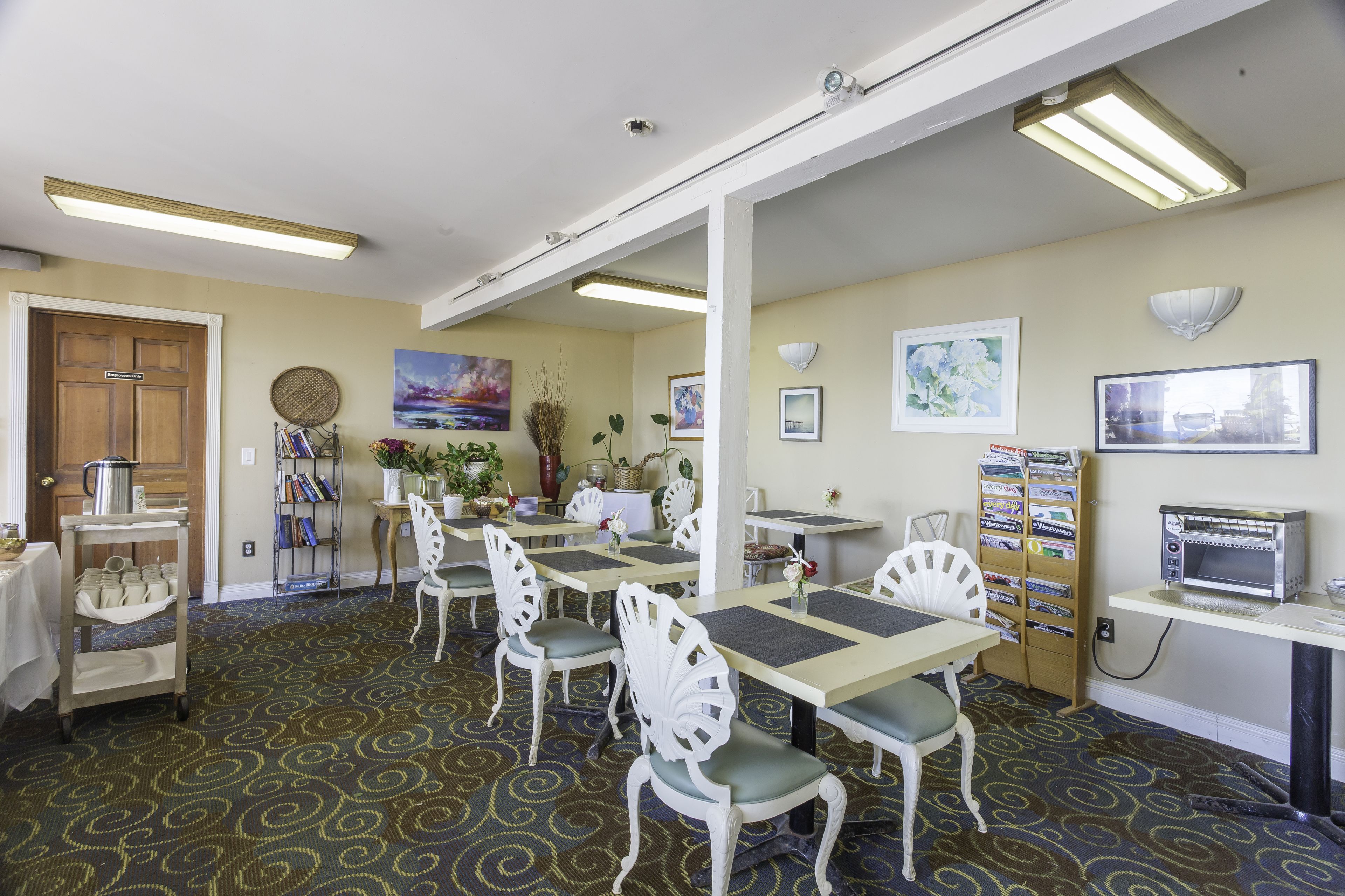 Un espace repas comprenant plusieurs tables et chaises, un chariot à café et un four à micro-ondes fixé au mur.