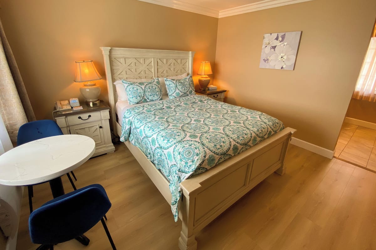 A bedroom with a bed, two bedside tables, a nightstand, a desk, and a chair.