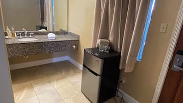 A bathroom with a sink, mirror, and a small refrigerator.